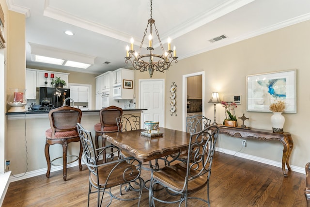 dining room with crown molding, visible vents, wood finished floors, and a raised ceiling
