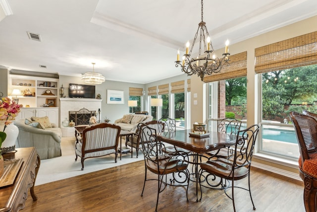 dining space with crown molding, a notable chandelier, wood finished floors, and visible vents