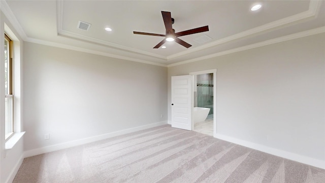 empty room with ceiling fan, light colored carpet, visible vents, a raised ceiling, and baseboards