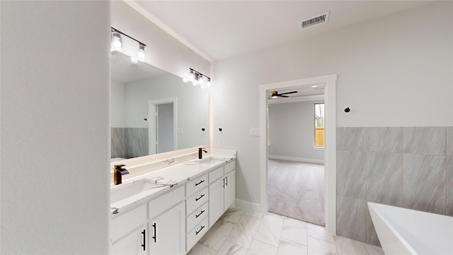 bathroom with visible vents, a sink, double vanity, and a soaking tub