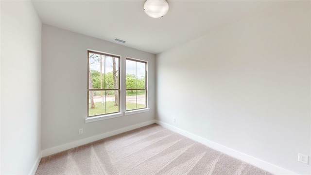 empty room featuring visible vents, baseboards, and light colored carpet
