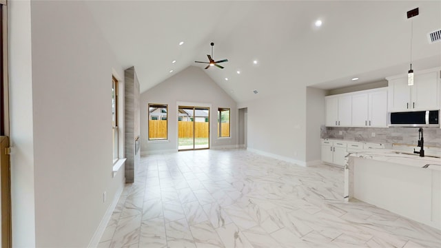 kitchen featuring stainless steel microwave, a ceiling fan, open floor plan, and marble finish floor
