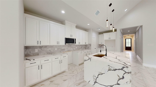 kitchen with a sink, decorative backsplash, stainless steel microwave, and visible vents