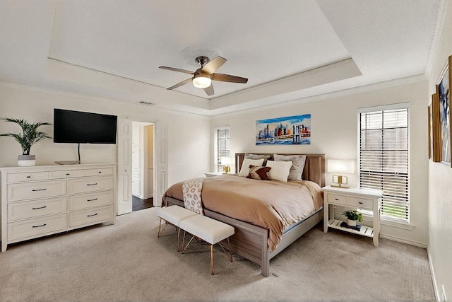bedroom featuring a tray ceiling, light colored carpet, multiple windows, crown molding, and ceiling fan