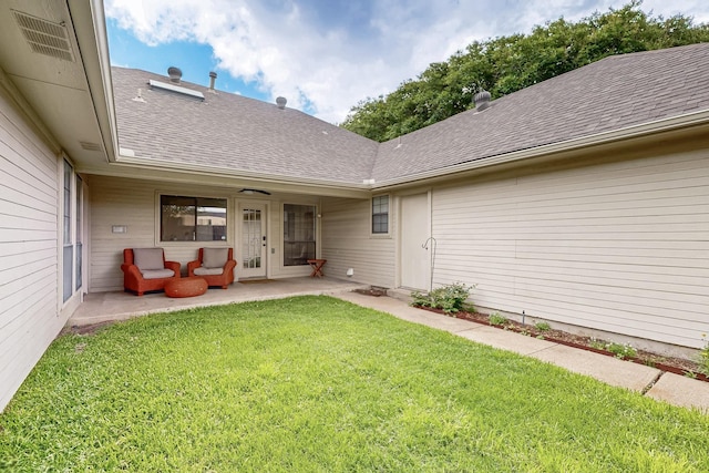 rear view of property featuring a patio, a shingled roof, and a lawn
