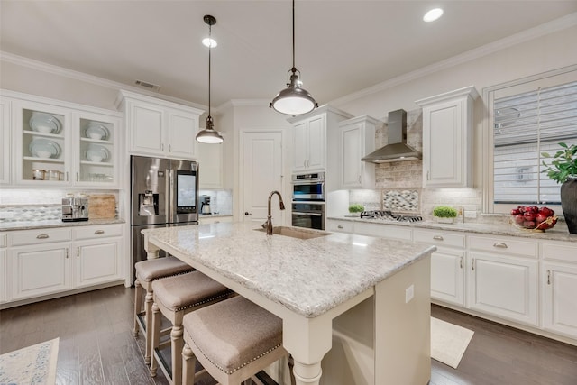 kitchen with visible vents, decorative backsplash, wall chimney range hood, a sink, and appliances with stainless steel finishes