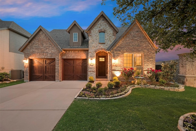 french country home featuring a yard, brick siding, central AC, and driveway