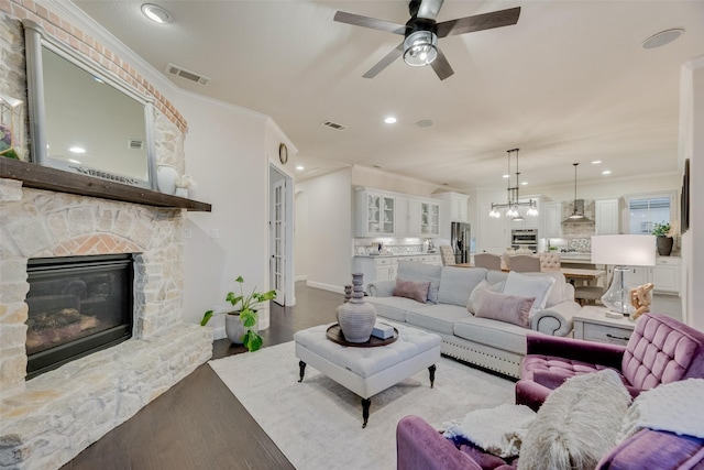 living area featuring ceiling fan, a fireplace, recessed lighting, visible vents, and ornamental molding