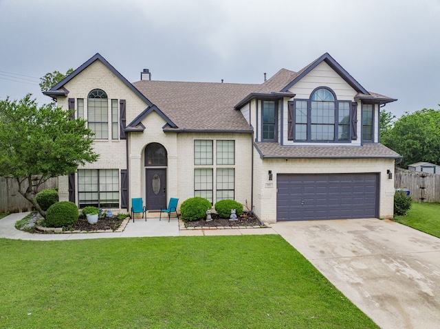 view of front of home featuring roof with shingles, brick siding, fence, a front lawn, and concrete driveway