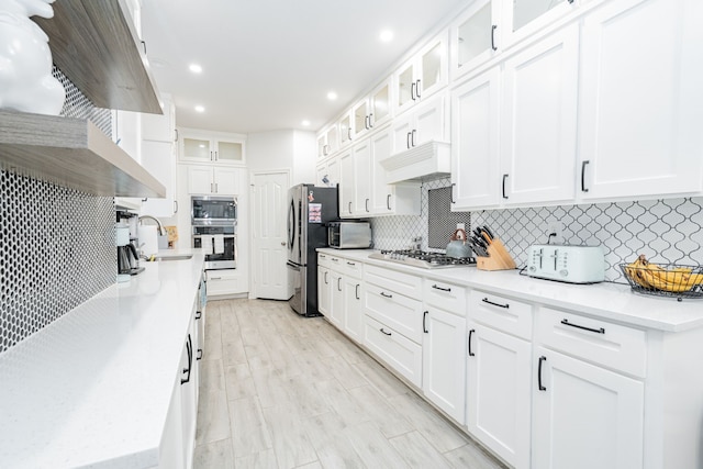 kitchen featuring custom range hood, a sink, white cabinets, stainless steel appliances, and recessed lighting