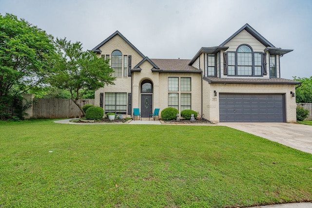 view of front facade with a front yard, brick siding, fence, concrete driveway, and an attached garage