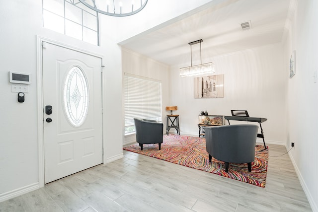 entrance foyer featuring visible vents, baseboards, light wood finished floors, and an inviting chandelier