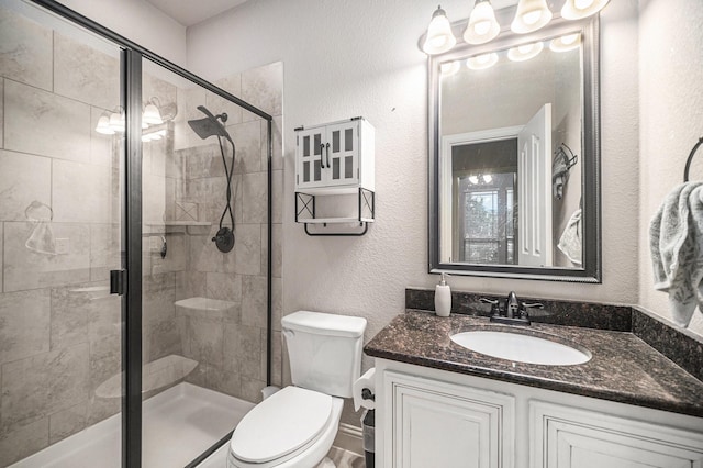 full bathroom featuring a shower stall, vanity, toilet, and a textured wall
