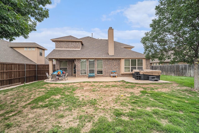 rear view of house with a hot tub, brick siding, a patio area, a chimney, and a shingled roof