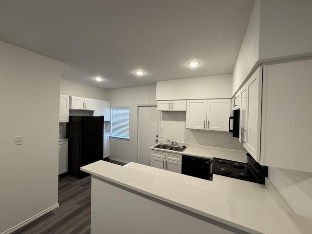 kitchen with dark wood finished floors, a sink, white cabinets, black appliances, and a peninsula