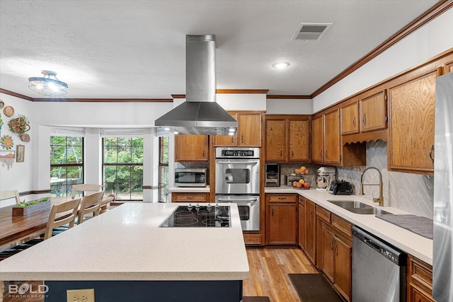 kitchen featuring a sink, appliances with stainless steel finishes, ornamental molding, and island exhaust hood
