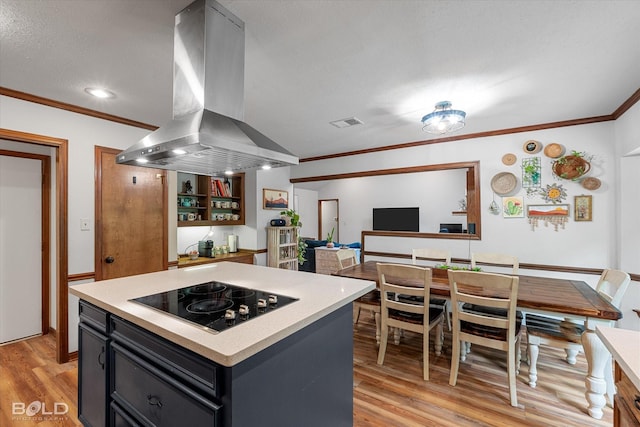 kitchen with crown molding, black electric stovetop, island range hood, and light wood-type flooring