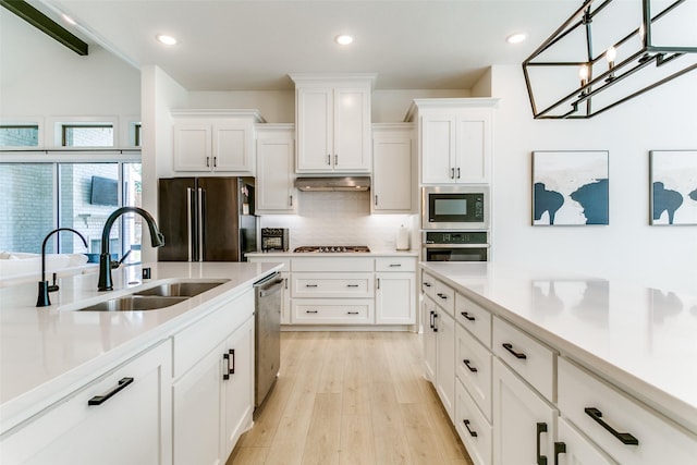 kitchen featuring tasteful backsplash, a sink, light countertops, stainless steel appliances, and white cabinetry