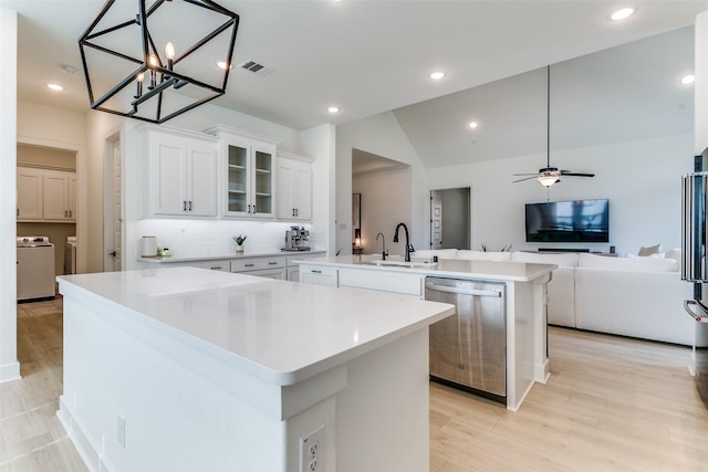 kitchen with a sink, dishwasher, separate washer and dryer, an island with sink, and visible vents