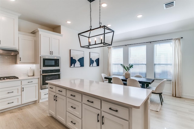 kitchen with backsplash, stainless steel appliances, visible vents, and light wood-style floors