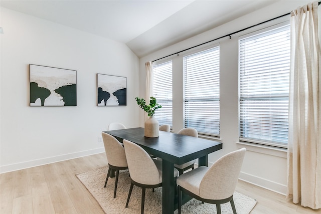 dining room with light wood-style floors, baseboards, and vaulted ceiling