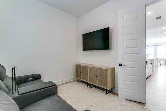 living room featuring baseboards, visible vents, and light wood finished floors