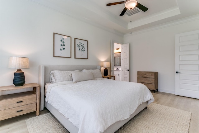 bedroom featuring ceiling fan, visible vents, crown molding, a raised ceiling, and light wood-style floors