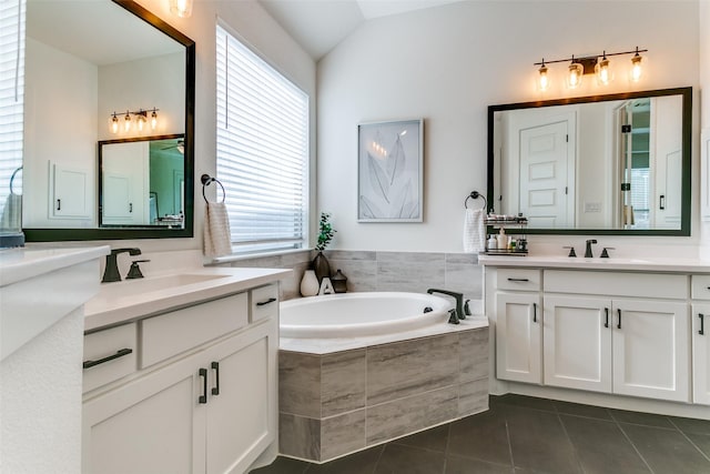 full bath with two vanities, a healthy amount of sunlight, tile patterned flooring, and a garden tub