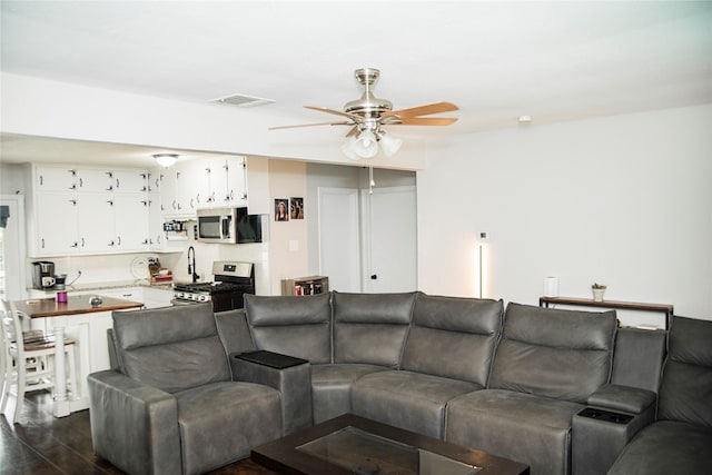 living room with ceiling fan, visible vents, and dark wood-style floors