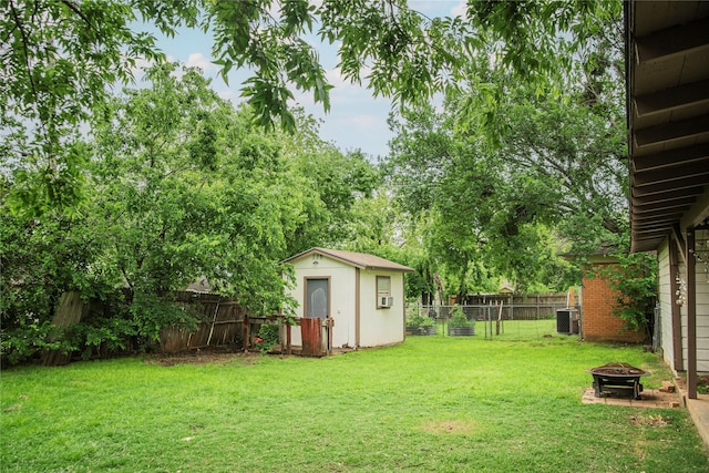 view of yard with a fenced backyard, an outdoor fire pit, a storage shed, and an outbuilding