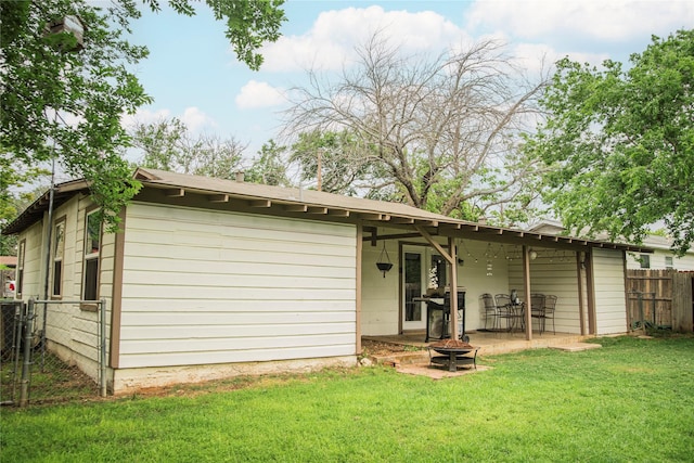 back of property with a patio, an outdoor fire pit, fence, and a yard