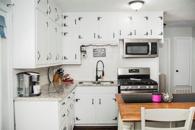 kitchen featuring visible vents, tasteful backsplash, a sink, stainless steel appliances, and white cabinetry