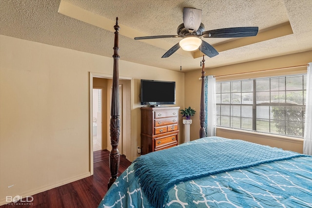 bedroom with a textured ceiling, dark wood-style floors, and baseboards