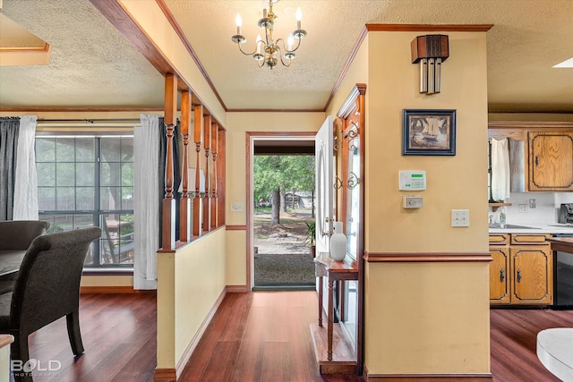 entryway with a textured ceiling, a notable chandelier, dark wood-style floors, and baseboards