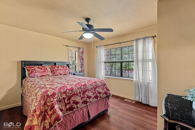 bedroom featuring baseboards, a textured ceiling, wood finished floors, and visible vents