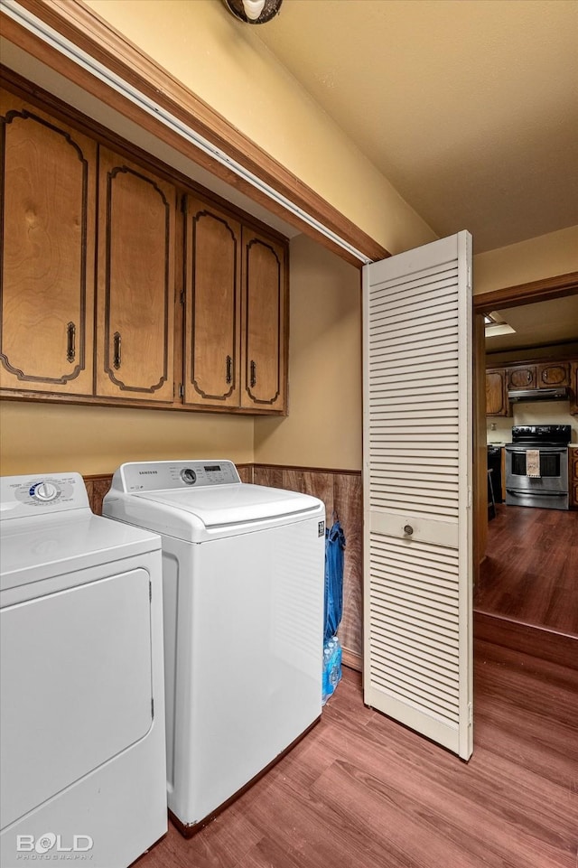 laundry room with separate washer and dryer, light wood-type flooring, and cabinet space