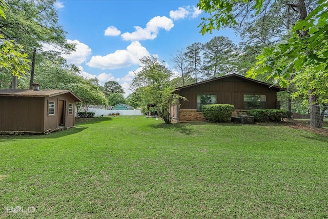 view of yard with a fenced backyard, a shed, and an outbuilding