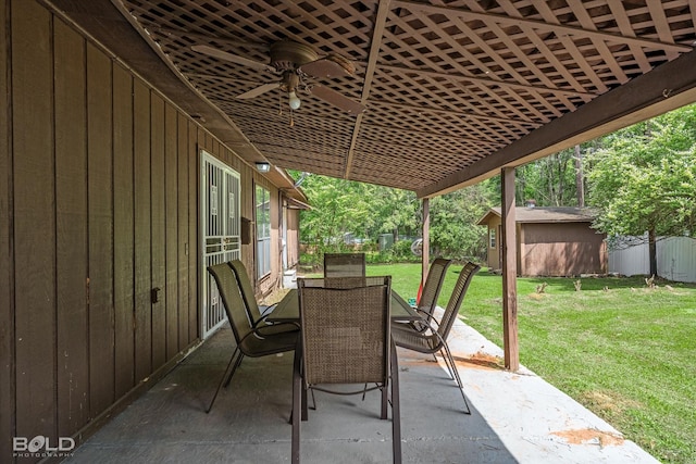 view of patio featuring a ceiling fan, a storage shed, an outbuilding, fence, and outdoor dining space
