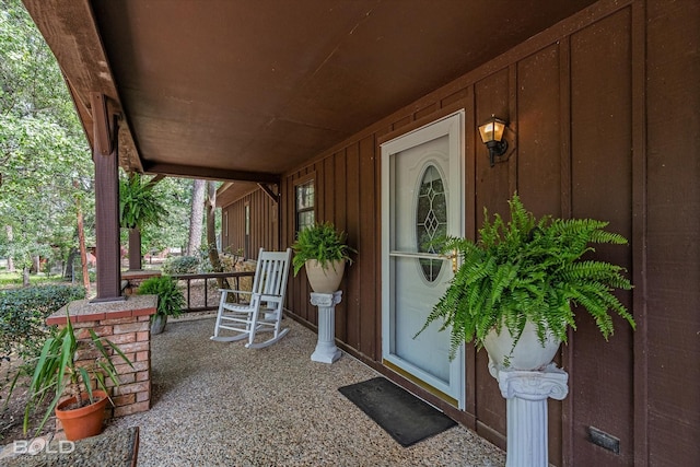 property entrance featuring covered porch and board and batten siding