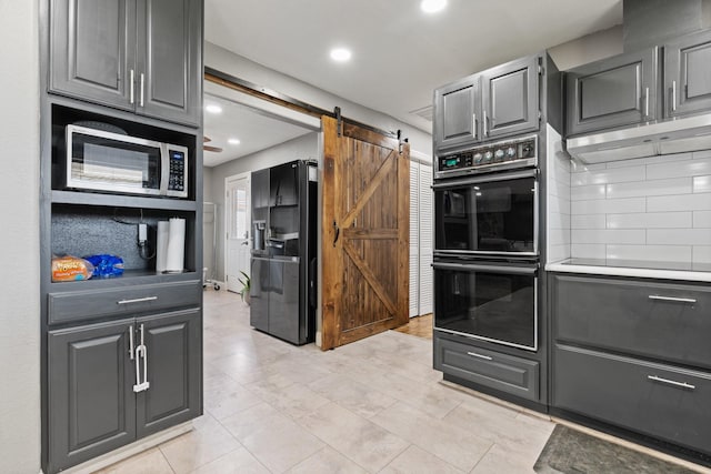 kitchen featuring a barn door, recessed lighting, decorative backsplash, gray cabinetry, and black appliances
