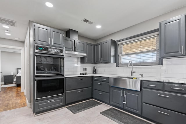 kitchen featuring visible vents, light countertops, a sink, backsplash, and black appliances
