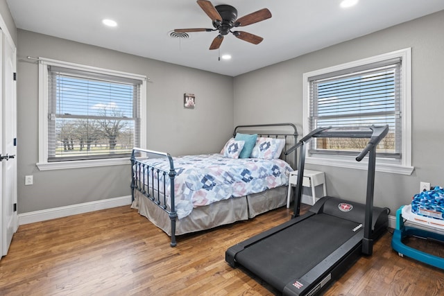 bedroom featuring baseboards, recessed lighting, wood finished floors, and multiple windows