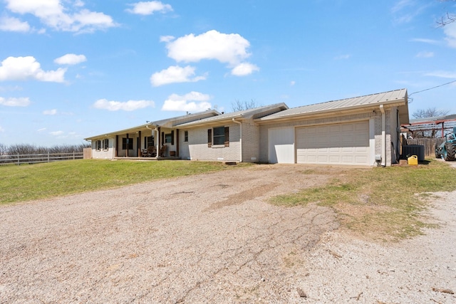 ranch-style house with fence, an attached garage, brick siding, dirt driveway, and a front yard