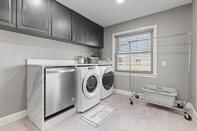 washroom featuring baseboards, washer and clothes dryer, and cabinet space