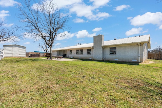 back of property featuring metal roof, a chimney, a patio area, brick siding, and a fenced backyard