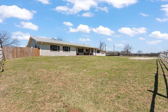 back of property featuring fence, a yard, metal roof, and brick siding