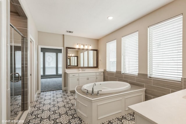 full bath with visible vents, a bath, vanity, and a shower stall