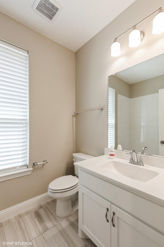 bathroom featuring visible vents, baseboards, toilet, and vanity