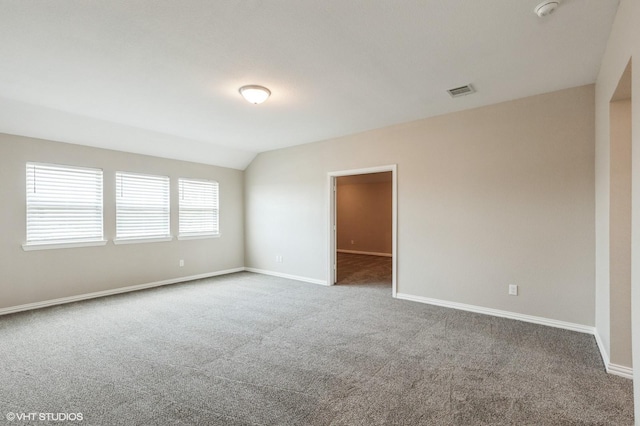 unfurnished room with baseboards, carpet, vaulted ceiling, and visible vents