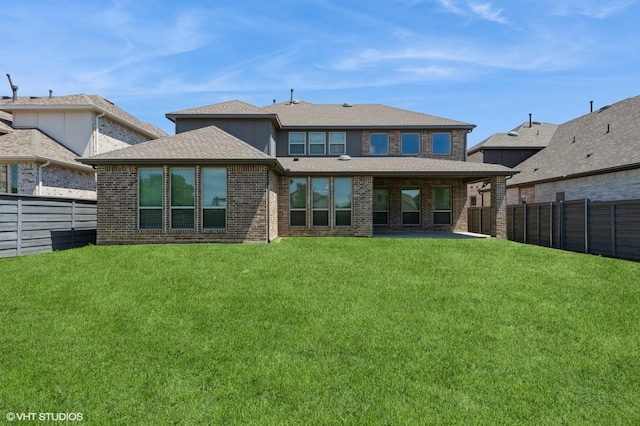 back of house featuring a fenced backyard, a lawn, roof with shingles, and brick siding